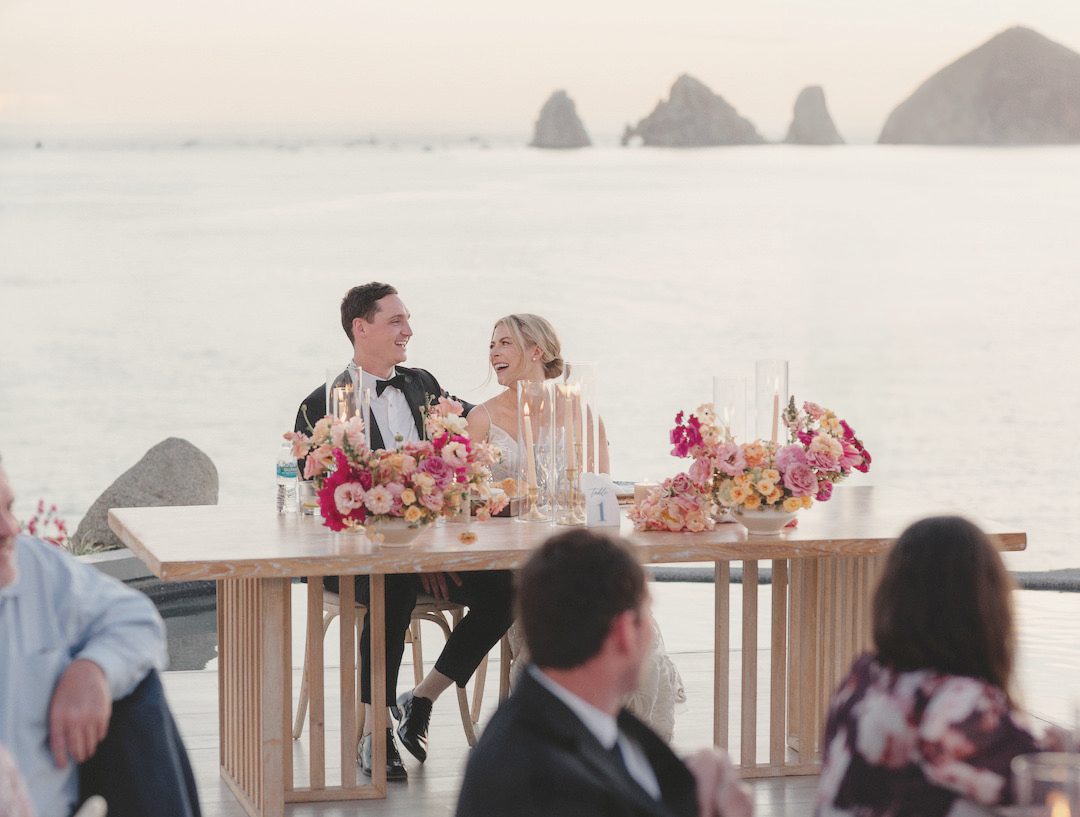 Newlyweds at their sweetheart table facing Land's End