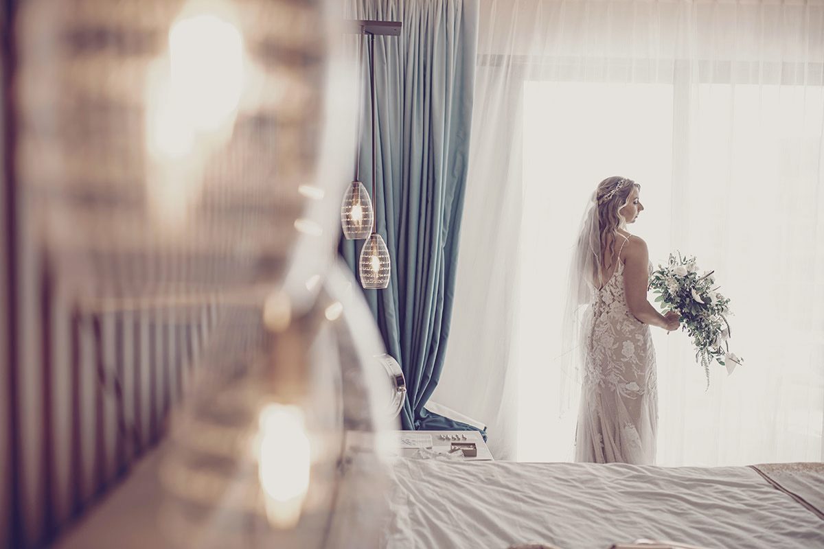 Bride by the window holding her bouquet