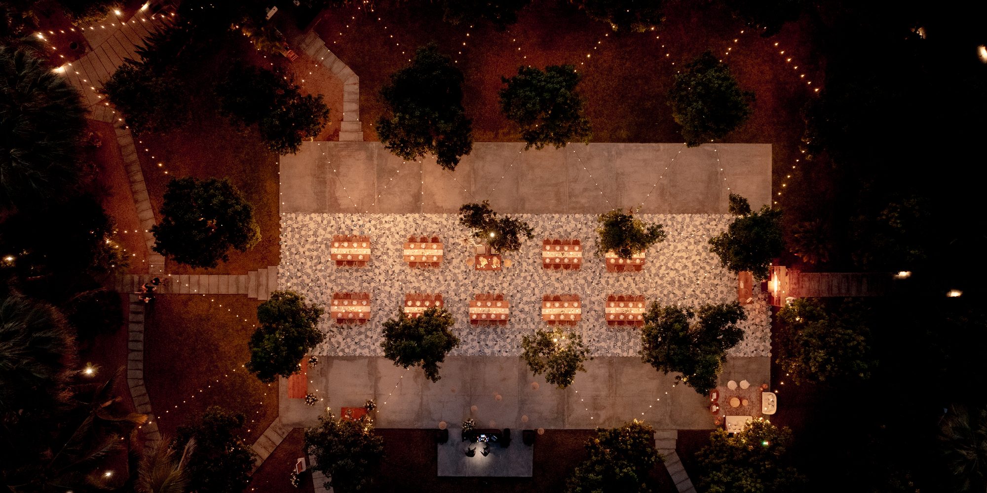 Aerial view of a candlelit reception among the trees at Acre at night