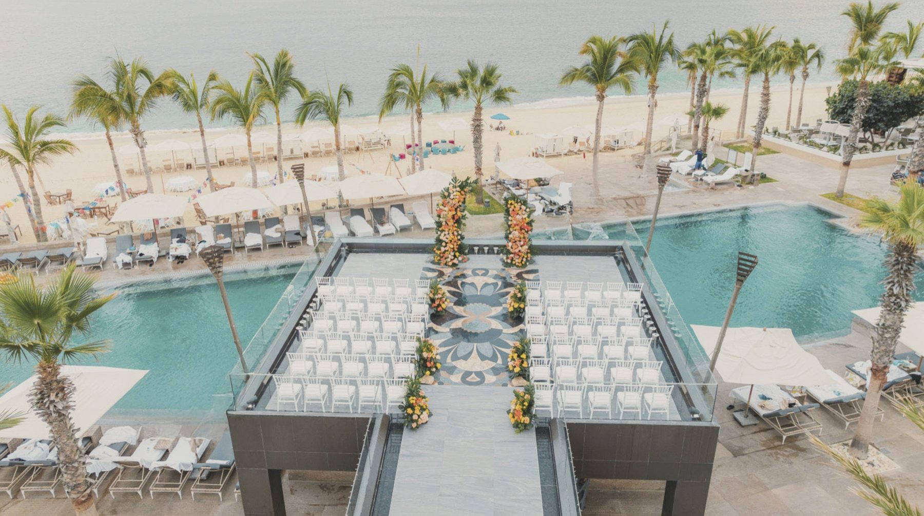 Aerial view of a poolside ceremony by the beach
