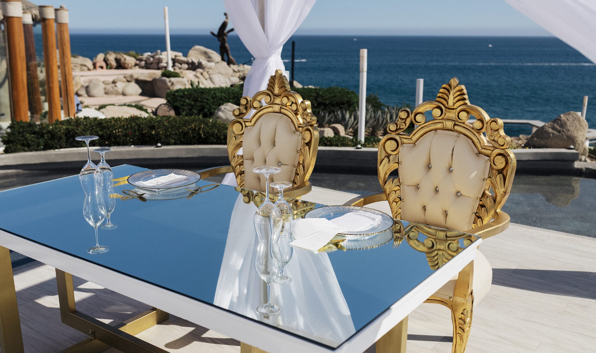 Mirror sweetheart table with gold chairs facing the sea at Sunset Monalisa
