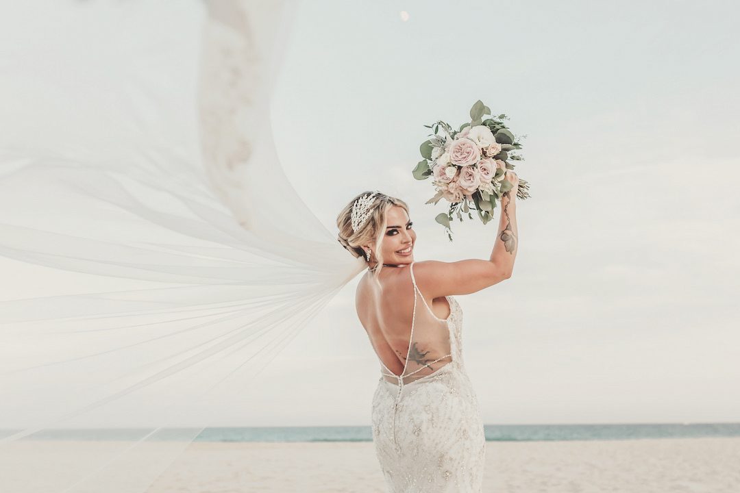 Bride with her veil in the wind on the beach