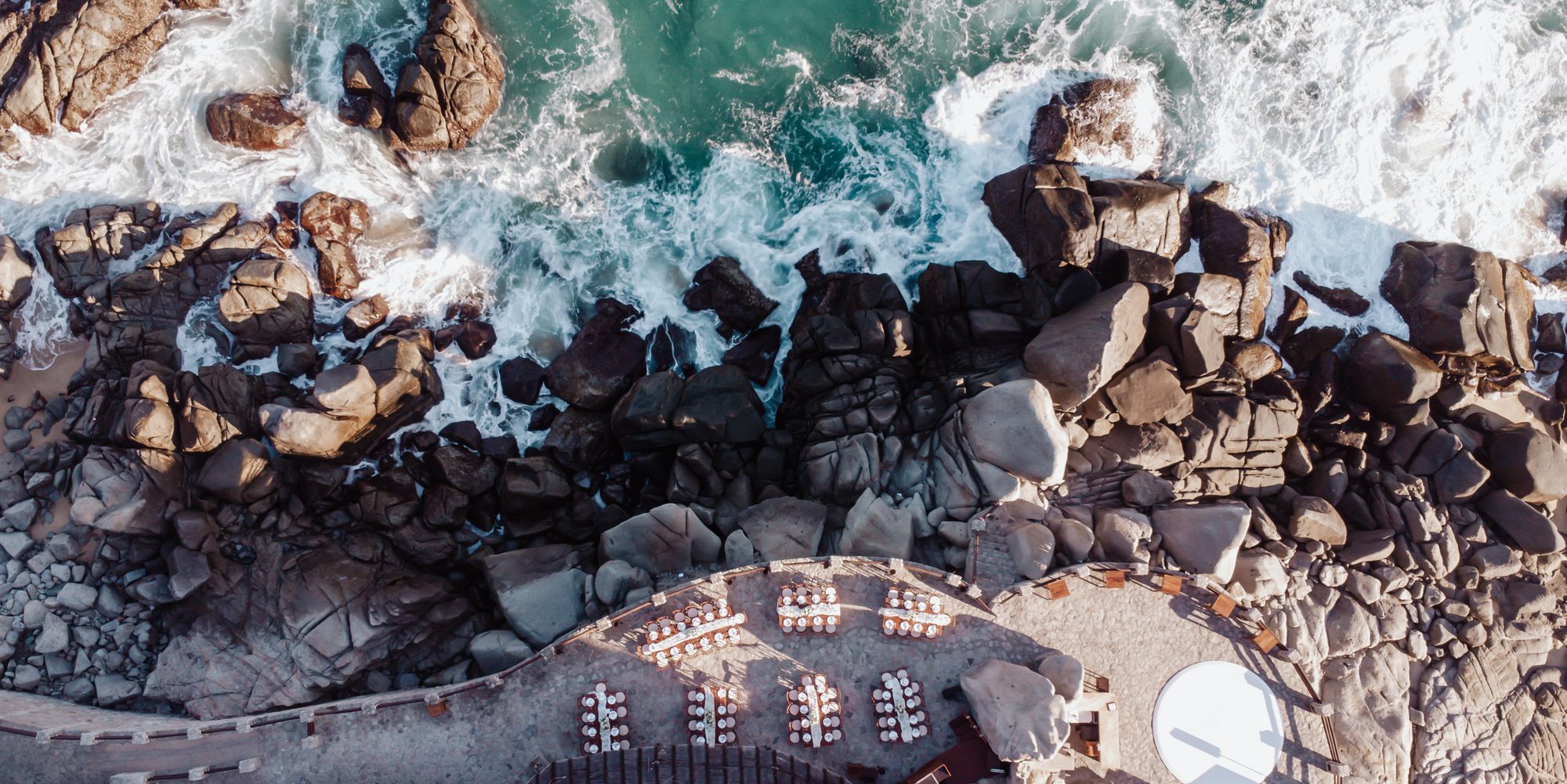 Aerial view of a cliffside dinner above the waves at Waldorf Astoria Pedregal